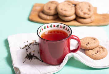 brewed black tea in a mug on a cotton napkin with cookies on a light background, top view