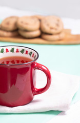 brewed black tea in a mug on a cotton napkin with cookies on a light background, top view