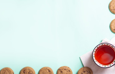 red Christmas mug with Christmas trees with black tea and homemade cookies on a napkin on a light background, close-up with copy space