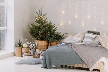 Christmas decorated bedroom interior with comfortable bed, Christmas fir tree and gift boxes on floor, copy space. Cozy home moment. Happy New Year. Christmas morning