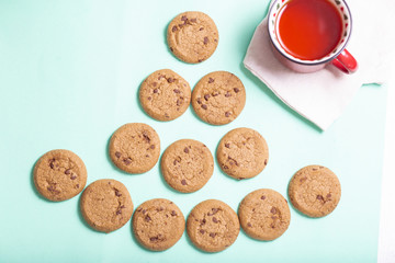 homemade cookies lies in the form of a Christmas tree and a mug of strong tea on a light background, top view