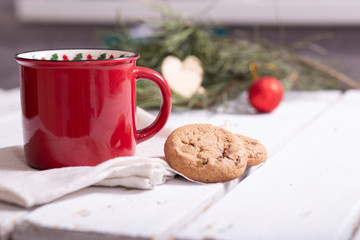 red christmas mug with tea, homemade cookies and fir branches on a light background