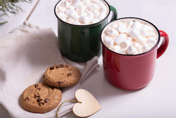 Red mug with cocoa and marshmallows and homemade cookies with chocolate, wooden heart - Christmas tree toy on a light background