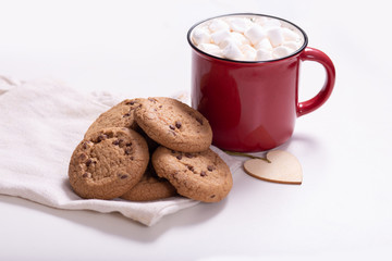 Red mug with cocoa and marshmallows and homemade cookies with chocolate, wooden heart - Christmas tree toy on a light background