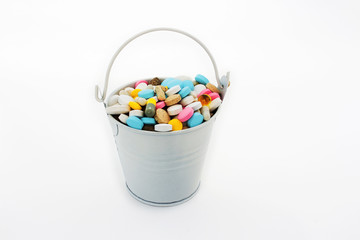 colored pills in a metal bucket on a white background, drugs in pill bucket