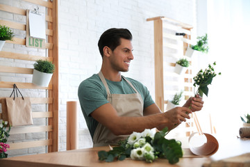 Florist making beautiful bouquet at table in workshop