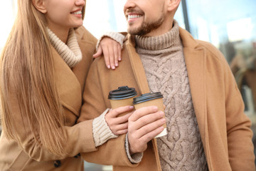 Couple with cups of coffee on city street in morning, closeup