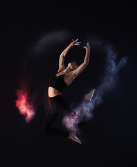 Professional acrobat with chalk powder exercising in dark studio