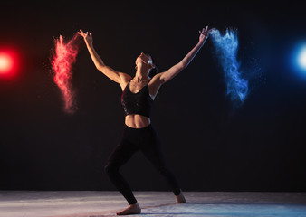 Professional acrobat with chalk powder exercising in dark studio
