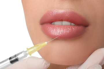 Woman getting lip injection on white background, closeup