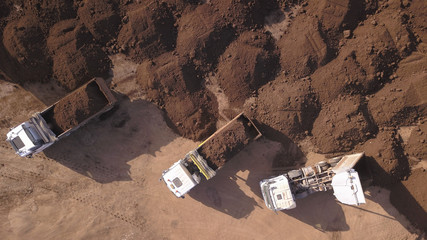 Dump truck unloading soil on a new construction site. Top view on Truck loaded with Soil.