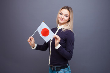 Immigration and the study of foreign languages, concept. A young smiling woman with a Japan flag in her hand.