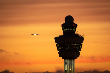 Amsterdam Schiphol International Airport control tower with a plane landing in the background...