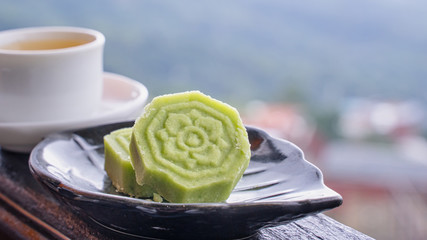 Delicious green mung bean cake with black tea plate on wooden railing of a teahouse in Taiwan with...