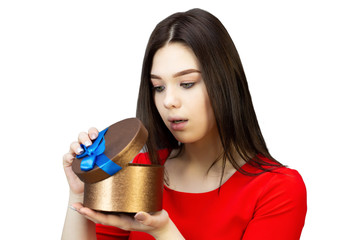 A teenager girl looks in surprise with disappointment and disappointment at an open gift. On a white background isolate. The woman looks in surprise at the gift box.