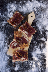  A cutting board  with  Traditional  tapas    with  spanish cured meat, bread chips with seed on background