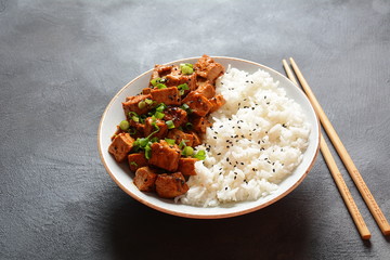 Sweet, spicy , crispy and fried Tofu in teriyaki sauce served in a bowl , sesame seeds and rice. Healthy vegan food, gluten-free