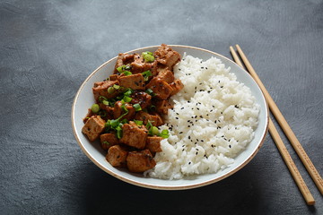 Sweet, spicy , crispy and fried Tofu in teriyaki sauce served in a bowl , sesame seeds and rice. Healthy vegan food, gluten-free