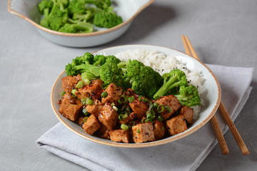 Sweet, spicy , crispy and fried Tofu in teriyaki sauce served in a bowl with broccoli, sesame seeds and rice. Healthy vegan food, gluten-free
