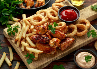 Fried Chicken wings with onion rings, french fries and dipping sauce. take away food.