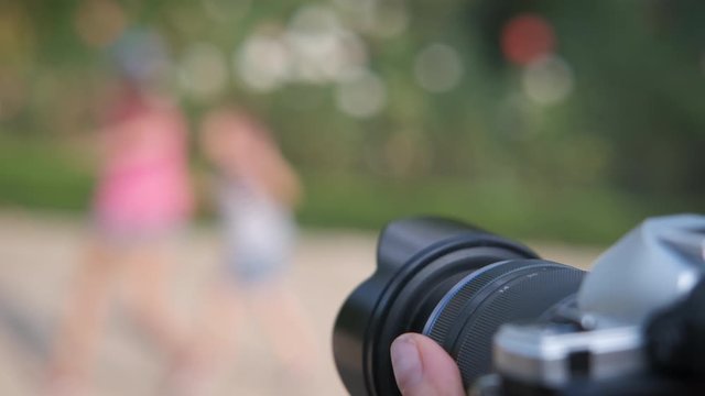 View of professional camera in park. The photographer takes pictures of cheerful children in the summer in the park.