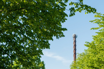 Between the leaves of the trees you see a rusty chimney pointing towards the sky