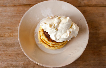 Russian traditional breakfast cottage cheese pancake in plate with sugar powder on wooden background