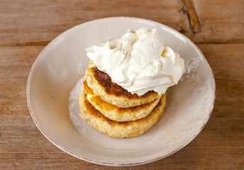 Russian traditional breakfast cottage cheese pancake in plate with sugar powder on wooden background