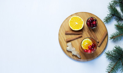 Orange and cranberry non-alcoholic punch with orange slices and spice on neutral pastel grey background.