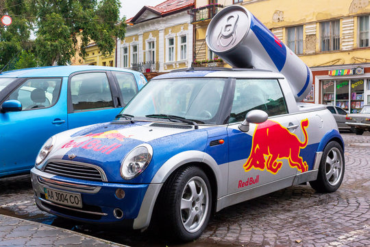 Red Bull mini cooper publicity car with a can of energy drink behind. fancy car tuning used for promotion. wet advertisement vehicle after the rain