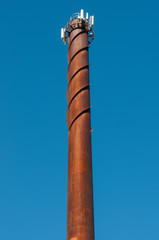 A rusty chimney pointing towards the the blue summer sky