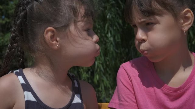 Having fun with sister. Faces with puff cheeks. Cheerful little sisters on a sunny day in the fresh air.
