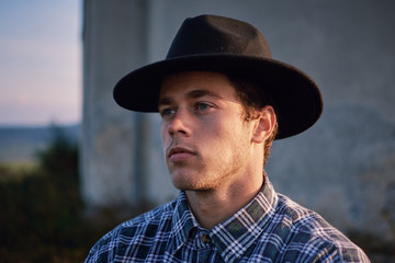 Portrait of western young handsome farmer at sunset looking satisfied with his work 