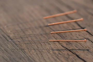 wood texture background four copper wire acupuncture needles on dark old aok wood