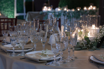 The napkin is decorated with a flower on a white plate. Close up. Table setting. Candles in glass vases