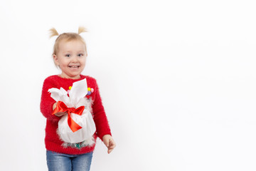 A little girl in a red sweater, blue jeans, with a gift in her hands, on a white background. The concept of a happy childhood. Blank space for text. The layout for the cards.
