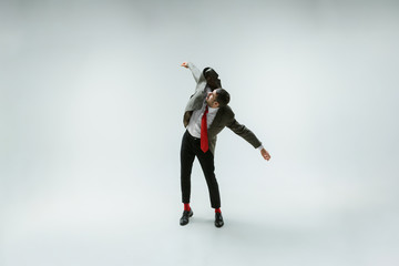 Young caucasian man moving flexible on white studio background. Male model in office attire bending...