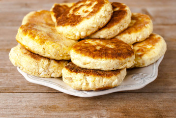 Russian traditional syrniki cottage cheese pancakes breakfast on the plate on wooden background