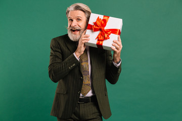 Photo of funky mature guy amour in khaki suit cupid character role showing big gift box on a Valentine Day isolated green color background