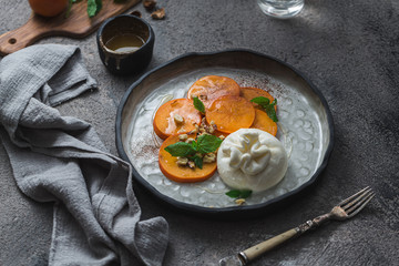 Buratta cheese with persimmon served on handmade plate