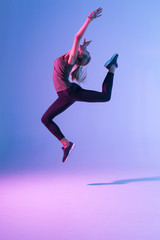 Handsome woman with perfect body jumping against colorful trendy background. Young athletic girl in jump