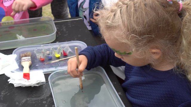 Pretty little blond girl paint on water ebru technology. Gimbal motion shot