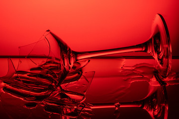 broken wineglass  lies on a glass mirror table in a red background