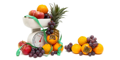 kitchen scales, fruits and measuring tape on a white background