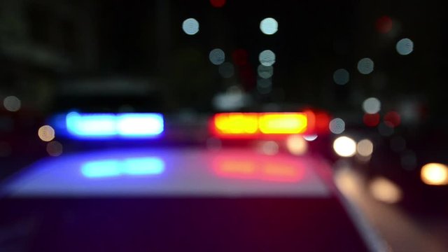 Police emergency lights flash at night. Flashlights. Police raid. Crime scene. Car accident and traffic jam. Blurred Flashing blue and red lights and signals on patrol car. Emergency car in action. 