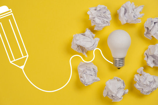 New Idea Concept With Crumpled Office Paper And White Light Bulb On Yellow Background. Creative Solution During Brainstorming Session Concept. Flat Lay, Top View, Copy Space