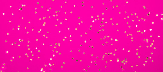 Small gold stars on pink crimson Magenta background Festive holiday background. Celebration concept. Top view,