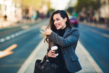 Happy beautiful professional business woman outdoors holding disposable paper cup.