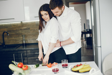 Lovely couple at home in a kithen. Woman and man prepare salad. Woman in a white shirt