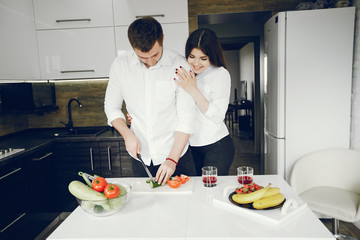 Lovely couple at home in a kithen. Woman and man prepare salad. Woman in a white shirt